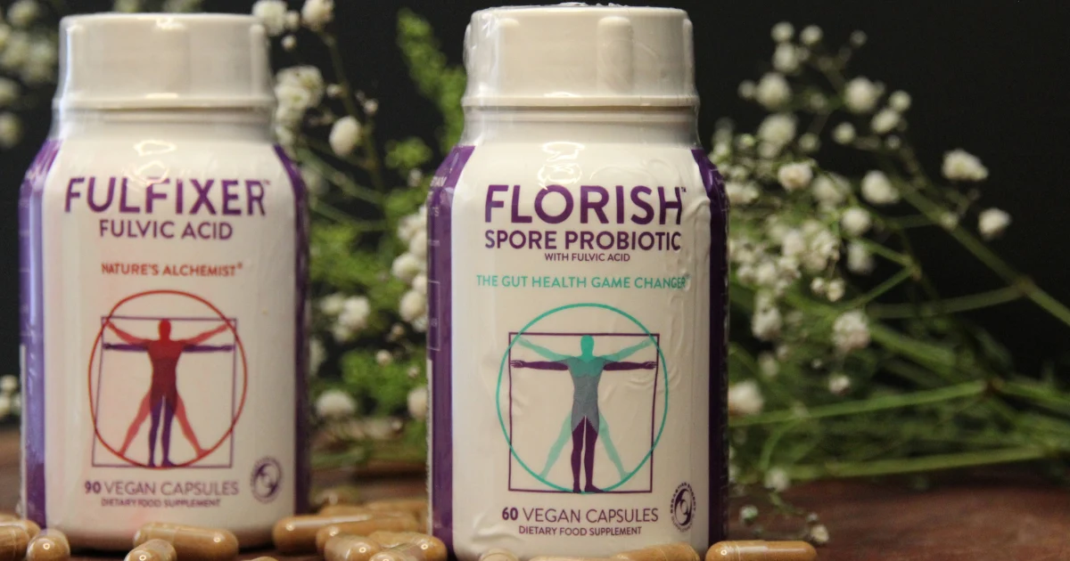 FLORISH Spore Probiotic and FULFIXER Fulvic Acid product bottles on a dark surface with baby's breath flowers